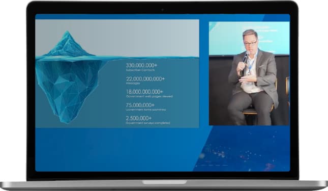 Slide outlining Granicus' government data points displayed next to Luke Norris speaking at a Granicus and Carasoft event.
