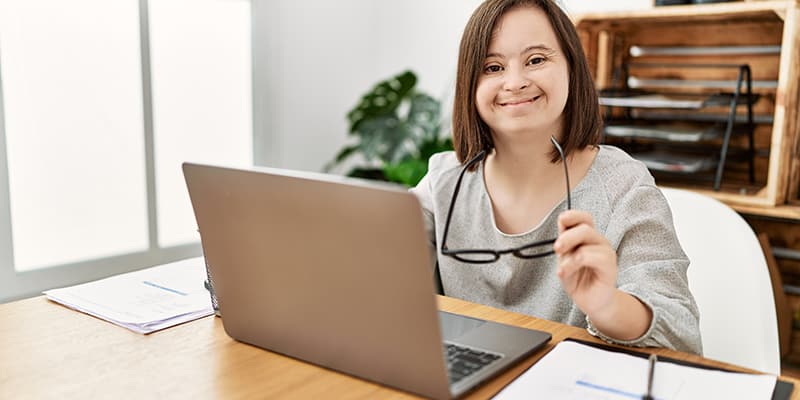 Smiling woman with a cognitive impairment using an accessible government service request platform.