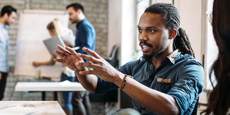 Team listening to their colleague explain a concept outlined on a desktop computer monitor.
