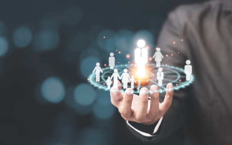 A hand holding a holographic image of people silhouettes.