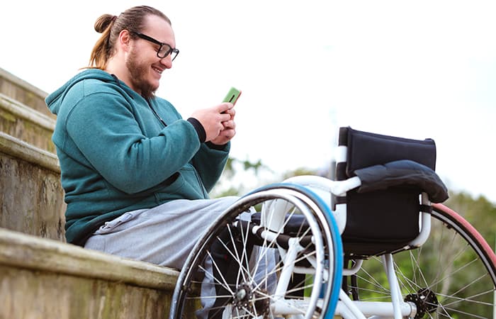 Man with wheelchair uses mobile phone to access local services, symbolizing how governments listen differently to improve digital experiences.
