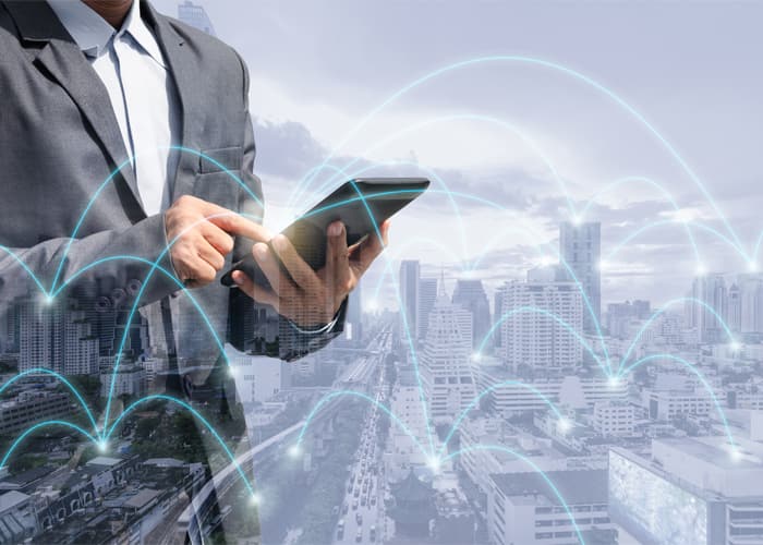 Businessman using smartphone with a city skyline background, representing wireless global internet, web network connectivity, and futuristic digital technology.