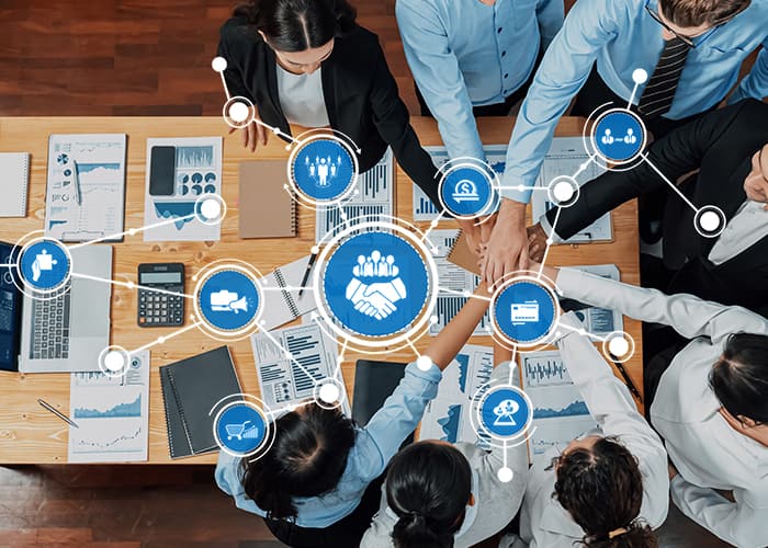 A top view of professionals collaborating in a modern office setting, analyzing data with charts and fostering partnerships through teamwork and strategic communication