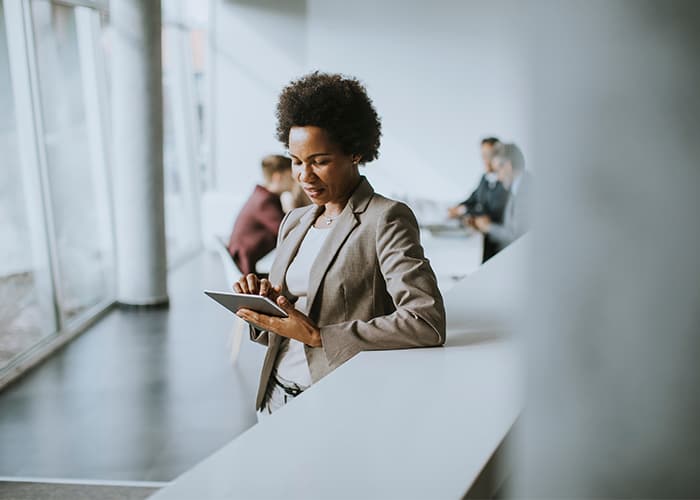 African American businesswoman standing and using digital tablet in a modern office