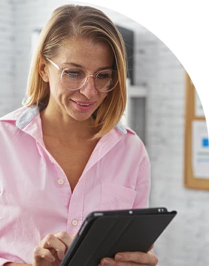 Middle-aged woman government employee in pink dress shirt viewing customized dashboards in a bright white office.