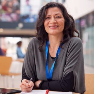 Middle-age Indian American woman wearing a name tag and working at a desk