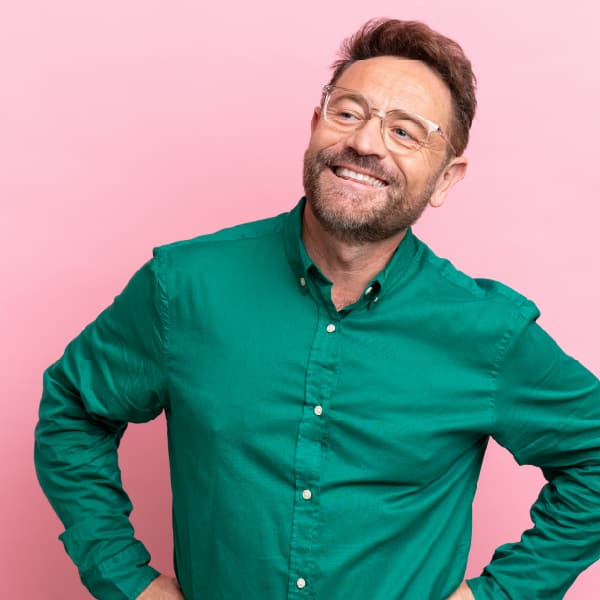 Hispanic male smiling standing in front of a pink wall