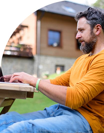 Man sitting on a bench in his backyard submitting a digital service request on his local government's online portal