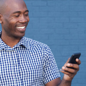 Image of a man looking at his phone and smiling, depicting connected technology