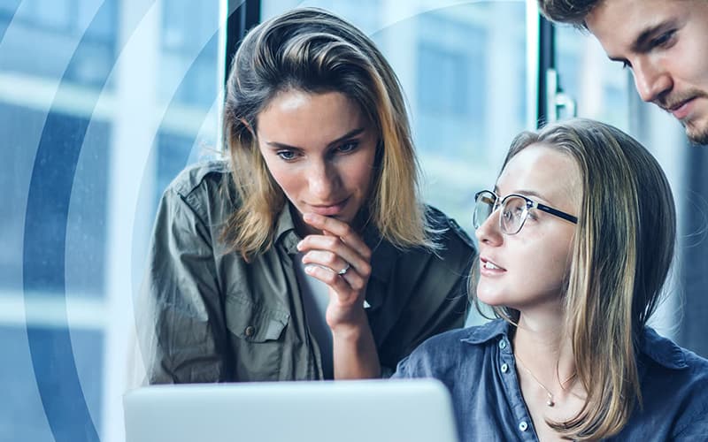 Three government employees in thought as they huddle over a laptop.
