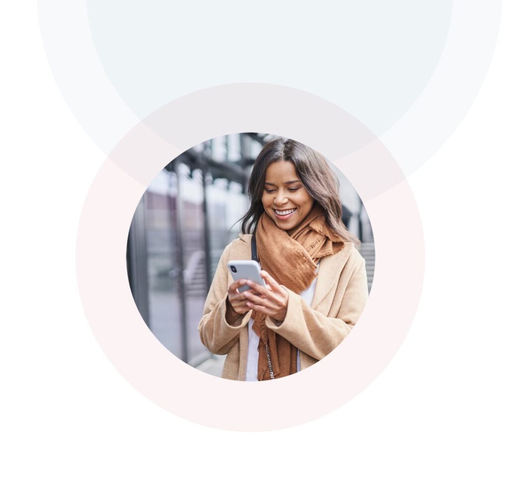 A woman smiling while using her smartphone