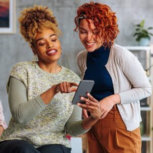 Two woman looking at a phone in a government office.