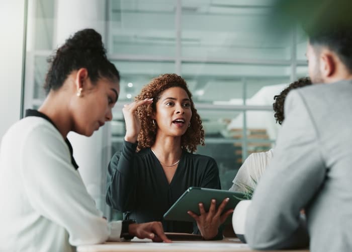A woman holding a tablet and explaining a scenario to a couple during a consultation.