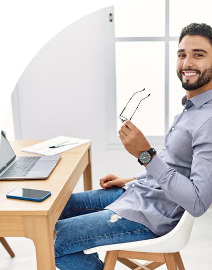 Young man smiling while working in front of a computer in a modern office