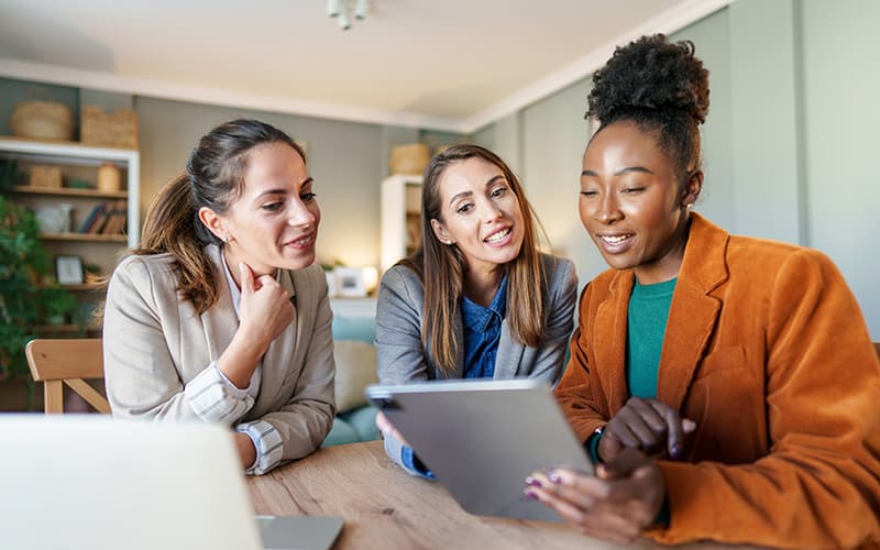 Three female government colleagues reviewing civic participation results using Operations Cloud on a laptop.
