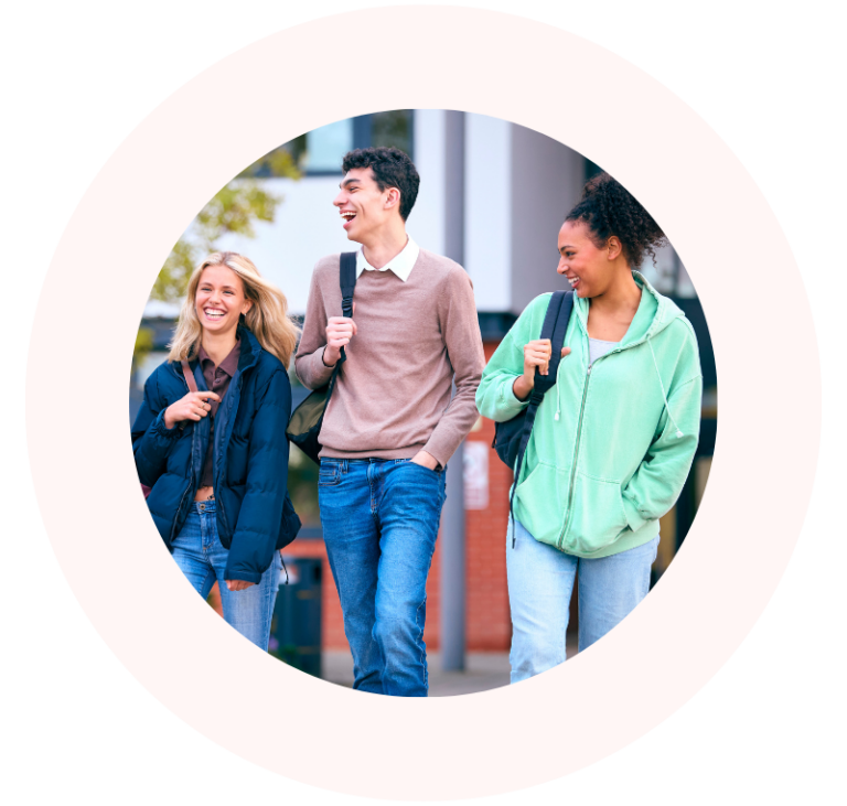 Three university students laughing as they walk together on campus.